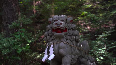 menacing and scary ancient japanese lion statue in temple inside forest - locked off view