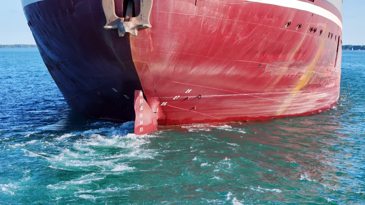Massive freighter rudder creating wake on vibrant blue waters of Detroit River