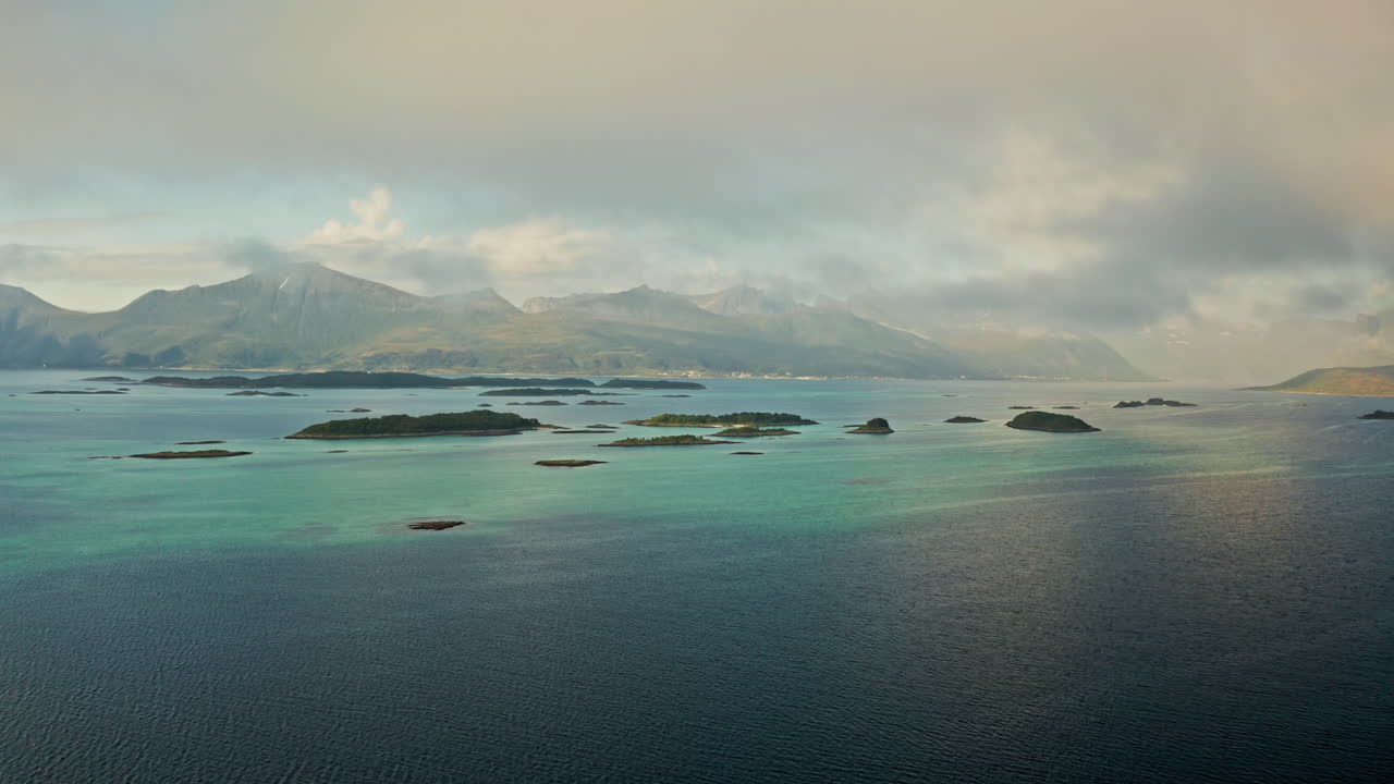 Aerial drone shot over the island of Senja in the Lofoten Ilsands, Norway. High view of the vibrant turquoise sea and the small islands. Breathtaking landscape, untouched natural wonder.