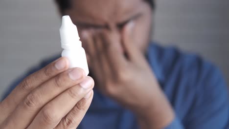 man holding eye drops, looking distressed