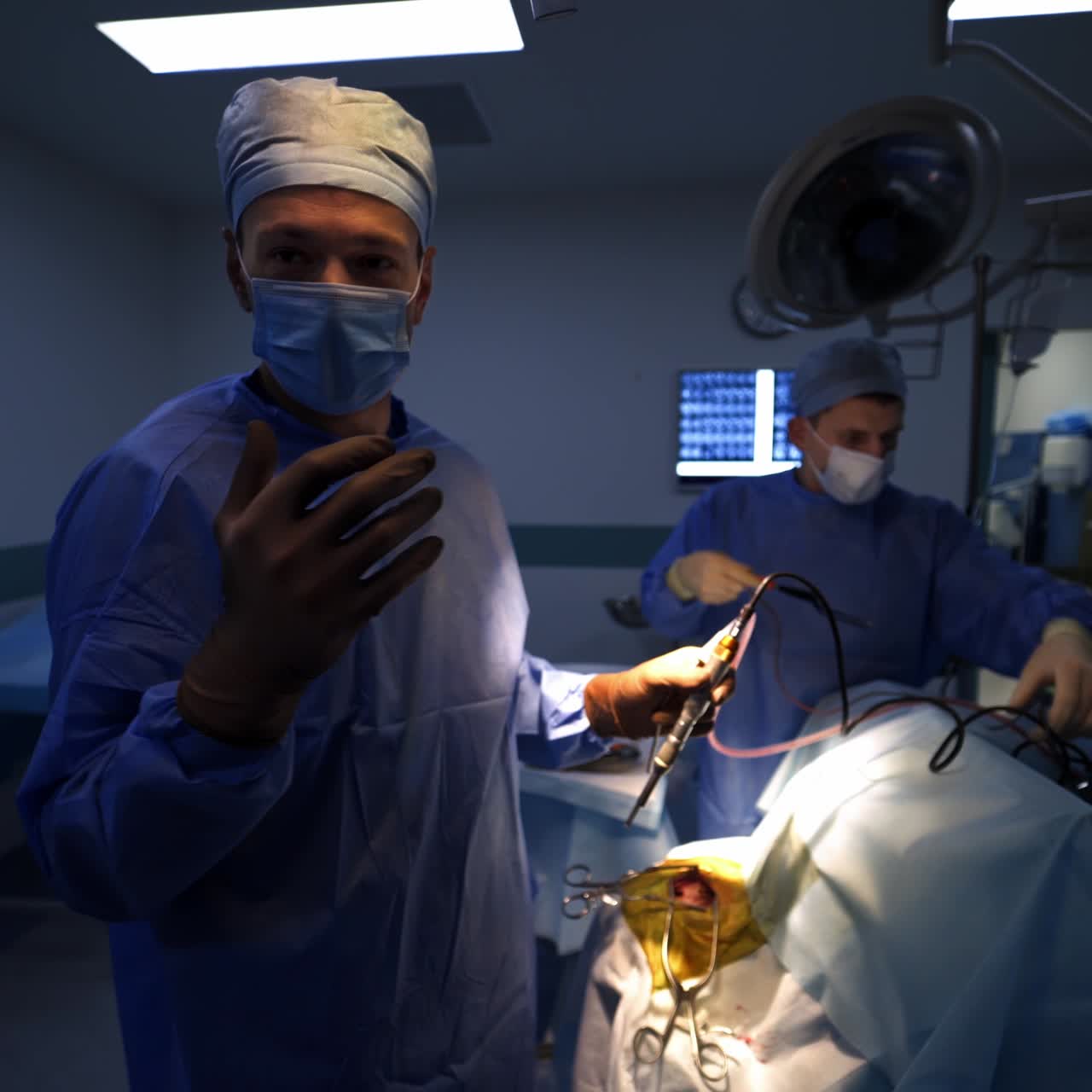Kirurg holder medicinsk værktøj til neurokirurgi på operationsstuen. Mandlig læge forklarer operationens forløb. Medicinske assistenter forbereder sig til operationen.
