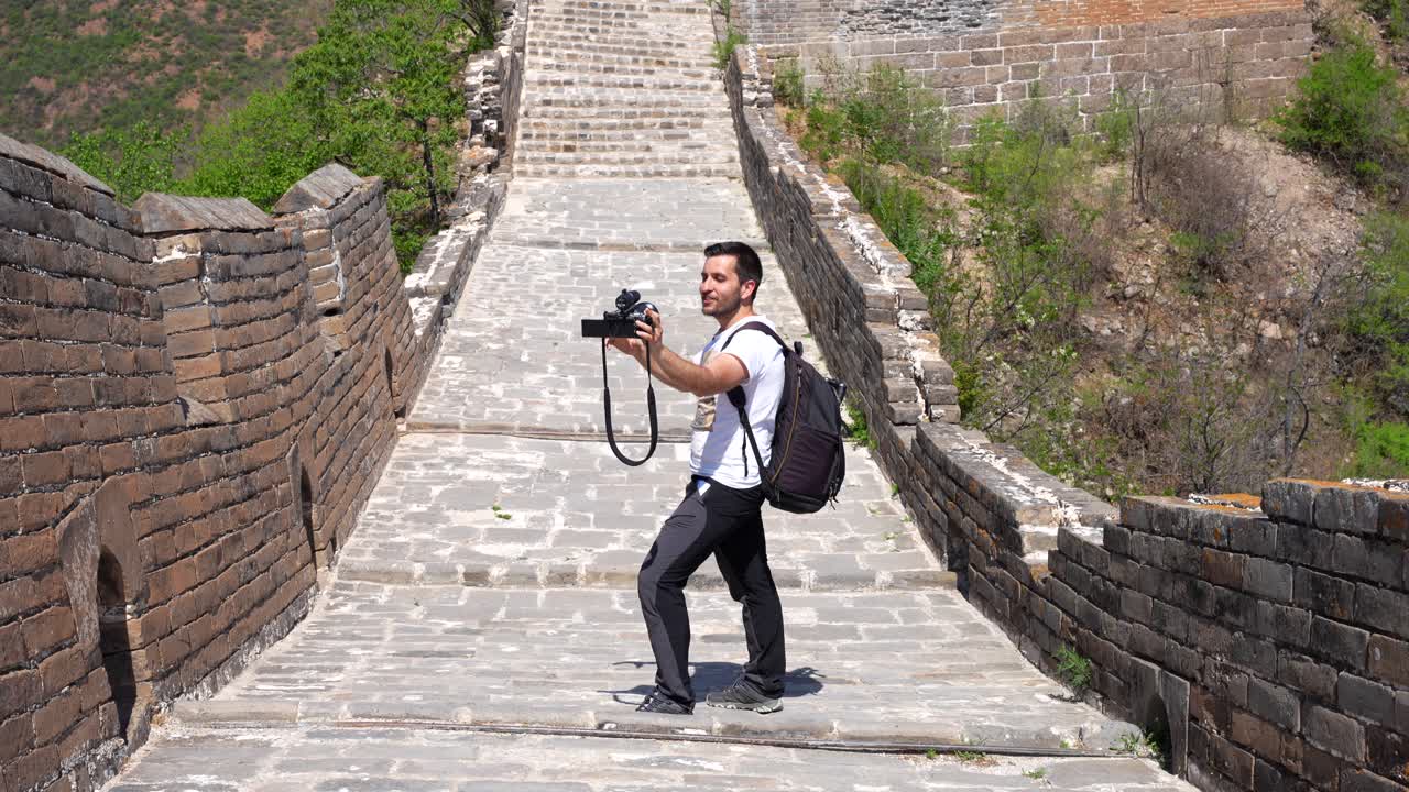 hombre vlogging sosteniendo una cámara con micrófono mientras está en la gran muralla de china