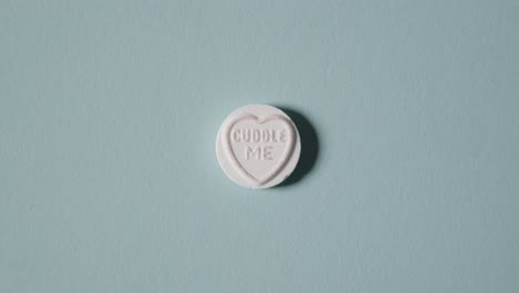 hand picking up heart candy with cuddle me message on blue background