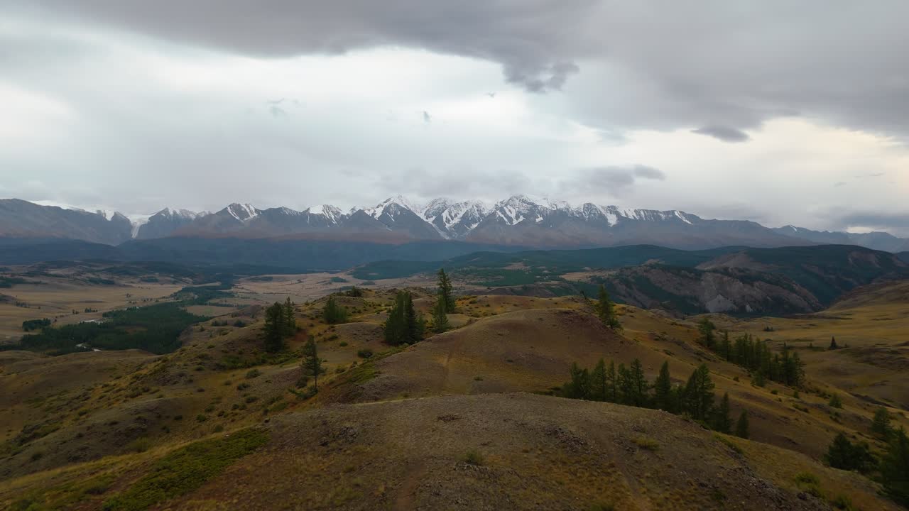 Aerial drone view of Mount Belukha in Altai Republic, Russia. Snow-capped peaks, valleys, and dramatic cloudy sky