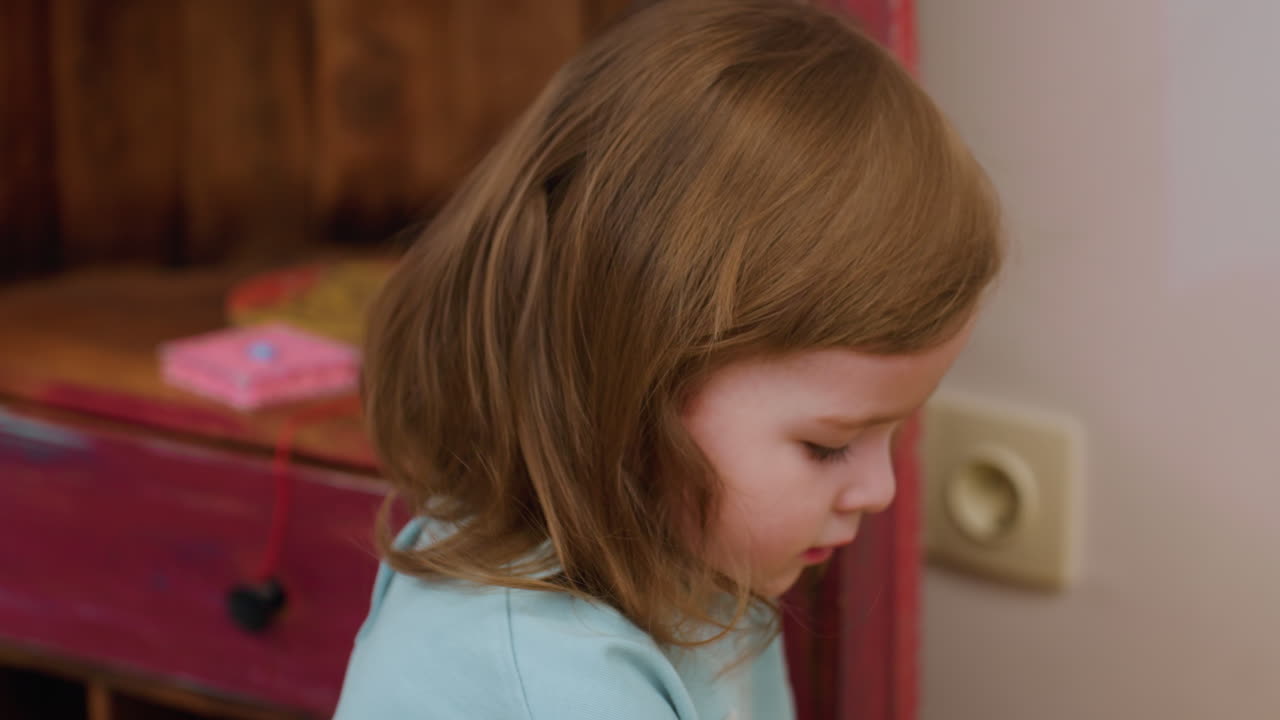 Beautiful capturing of child brown hair well styled in soft light, focus on strands, gentle movement, toys in background blurred into foggy shapes, calm indoor mood, tender detail, cozy composition