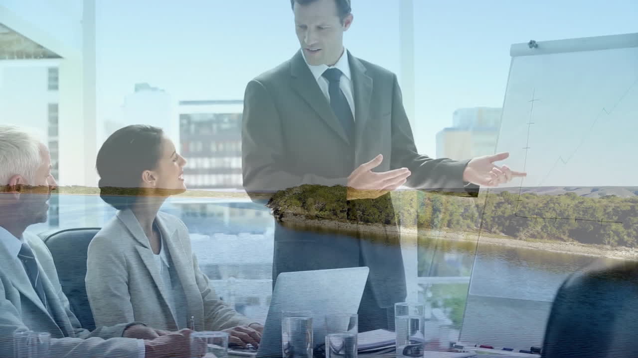Discussing charts, diverse professionals in business meeting overlooking coastal landscape