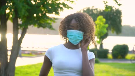 african american girl removes a medical mask at park. end of quarantine