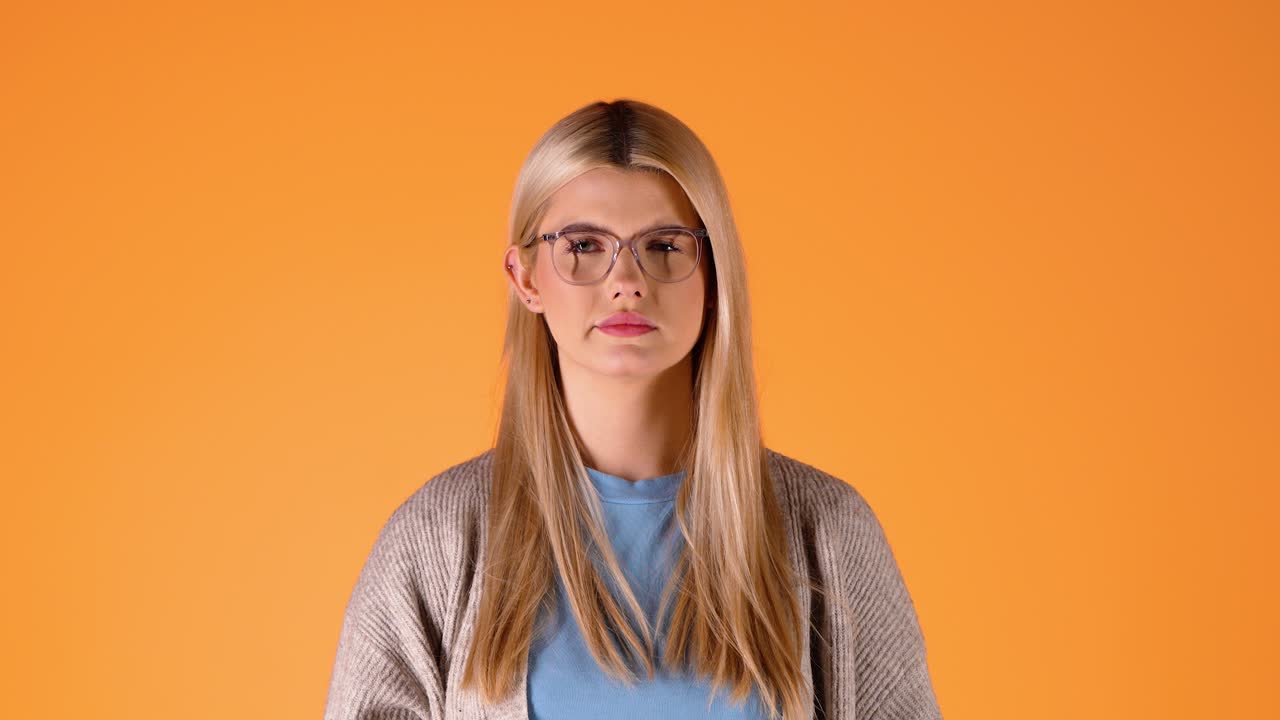 Blonde woman with high temperature sneezes in tissue and blows nose, orange