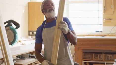 carpintero afroamericano buscando y eligiendo un tablón de madera en una carpintería