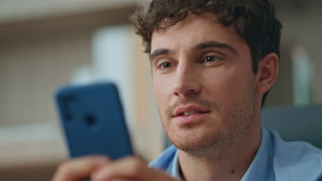 happy freelancer chatting online looking smartphone screen in office closeup.