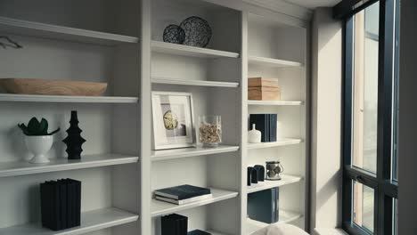 neatly-decorated-large-white-shelving-with-photos-and-books-next-to-a-window-letting-in-natural-sunlight