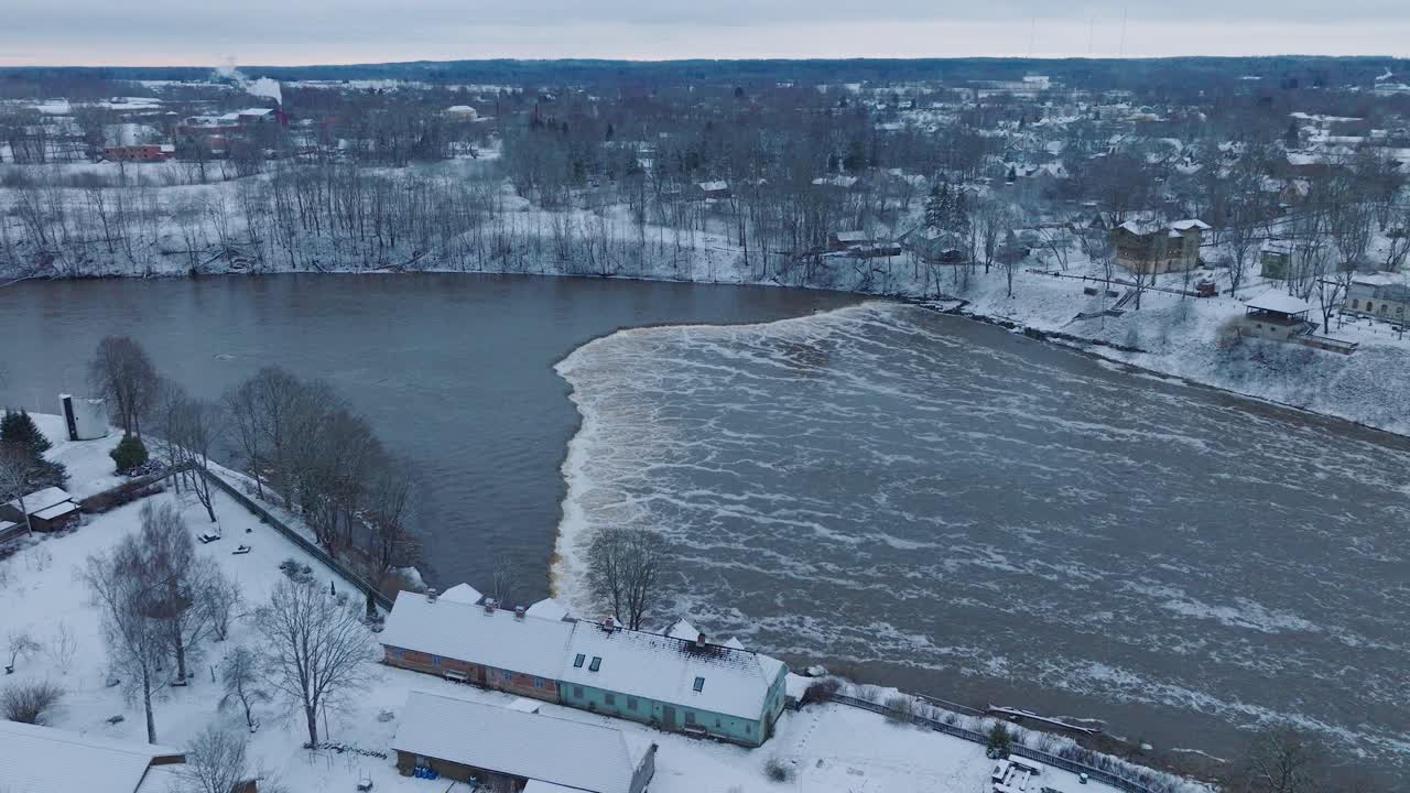 vista aérea de los rápidos del río venta durante las inundaciones de invierno, kuldiga, letonia, día de invierno nublado, amplia toma de drone moviéndose hacia adelante inclinándose hacia abajo