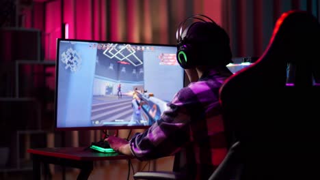 un adolescente asiático emocionado celebra la victoria y baila mientras juega videojuegos en la computadora, videojuegos de disparos en línea