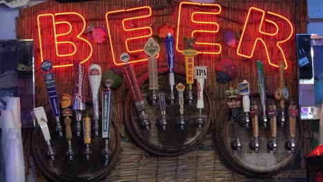 a neon sign at a tiki bar advertises beer