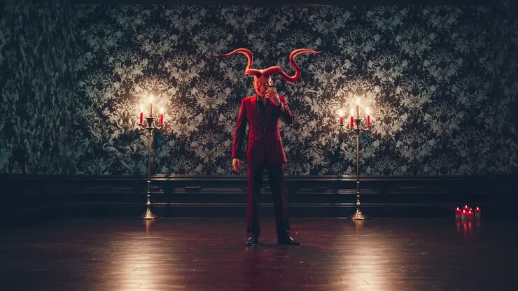 Elegant devil dressed in a striking red suit and sporting horns is taking a selfie with a smartphone, surrounded by a vintage room softly illuminated by candelabras
