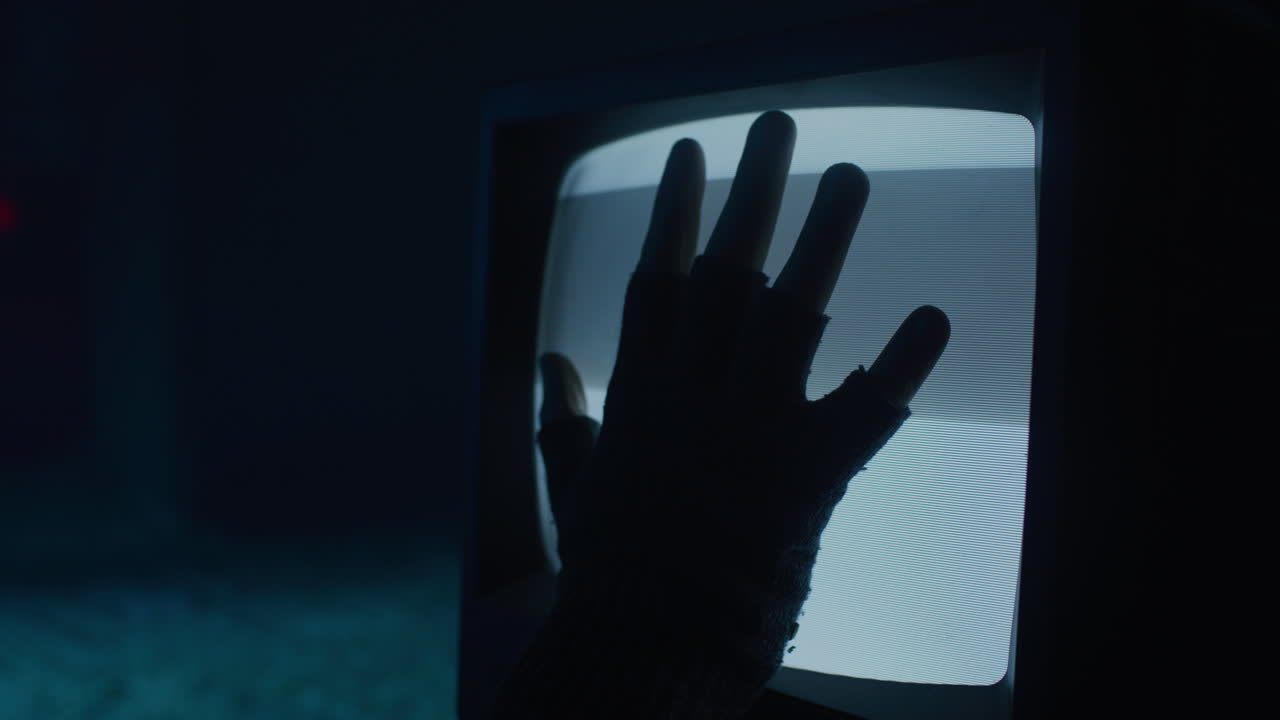 Gloved Hand on Vintage TV Screen at Night