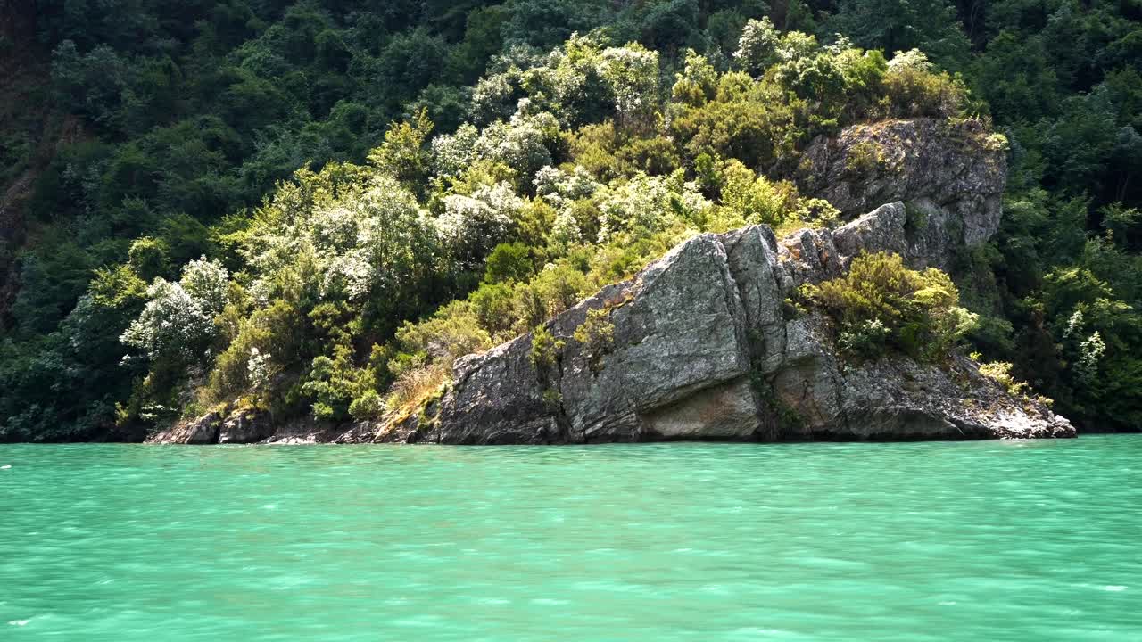 Albania, Lago Koman, vista di rocce lungo la riva boscosa.