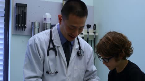 Junger-Asiatischer-Männlicher-Arzt,-Der-Den-Blutzuckerspiegel-Eines-Jungen-Mit-Einem-Glukometer-4k-Misst