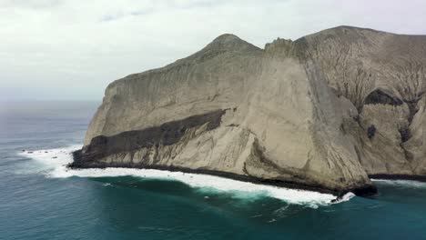 Escarpados-Acantilados-Rocosos-Caen-Hacia-Las-Aguas-Costeras,-Retroceso-Aéreo,-Islas-San-Benedicto-Revillagigedo