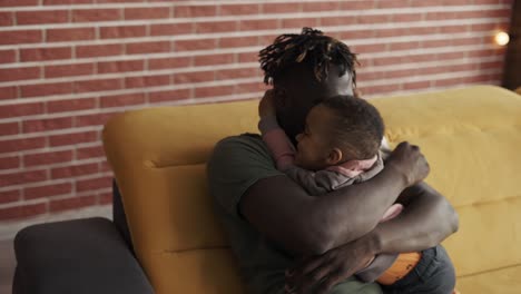 Afro-american-dad-playing-with-small-kid-boy-hugging,-cuddling-together-at-home