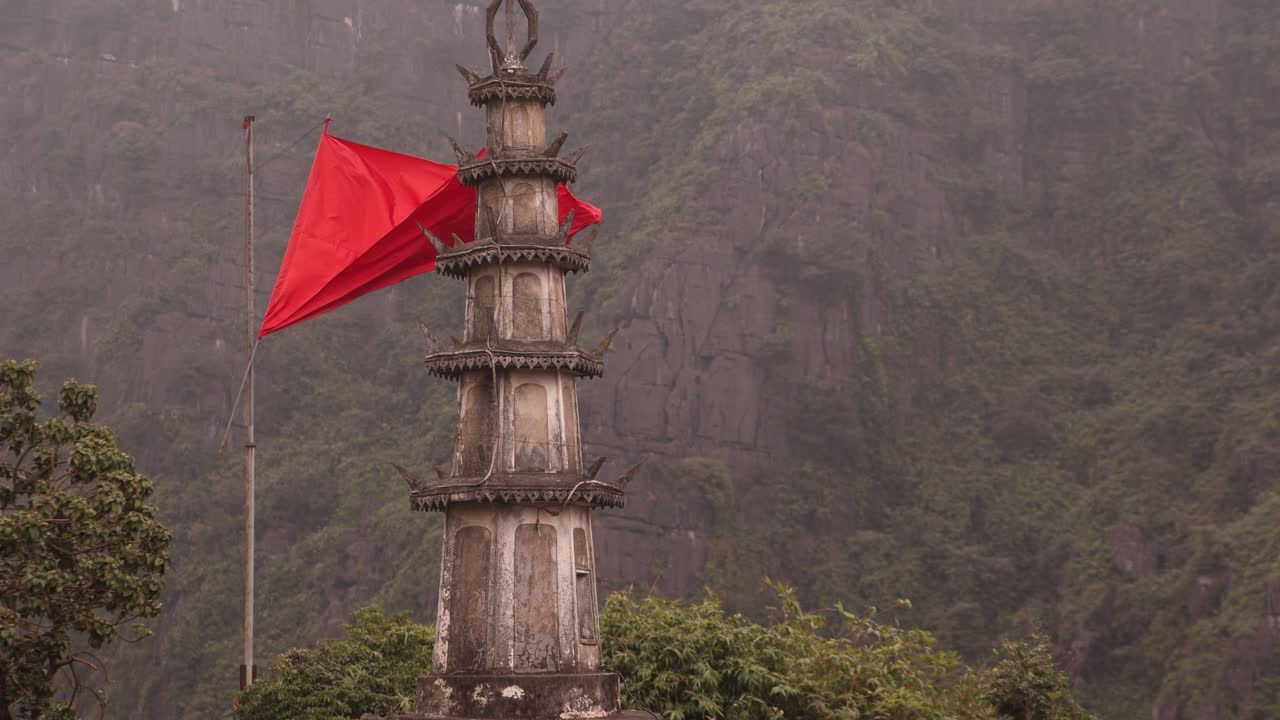 Vietnamese flag waving in front of towering pagoda in the mountainous region of Ninh Ninh in Northern Vietnam