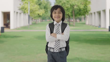 niño de escuela indio de pie con las manos cruzadas