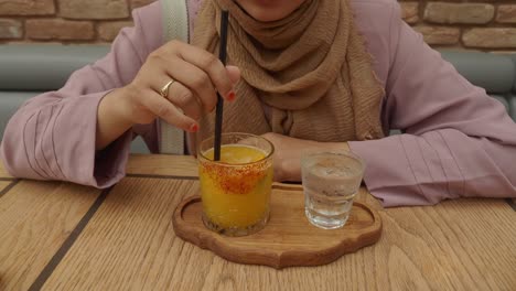 woman drinking orange juice at a cafe