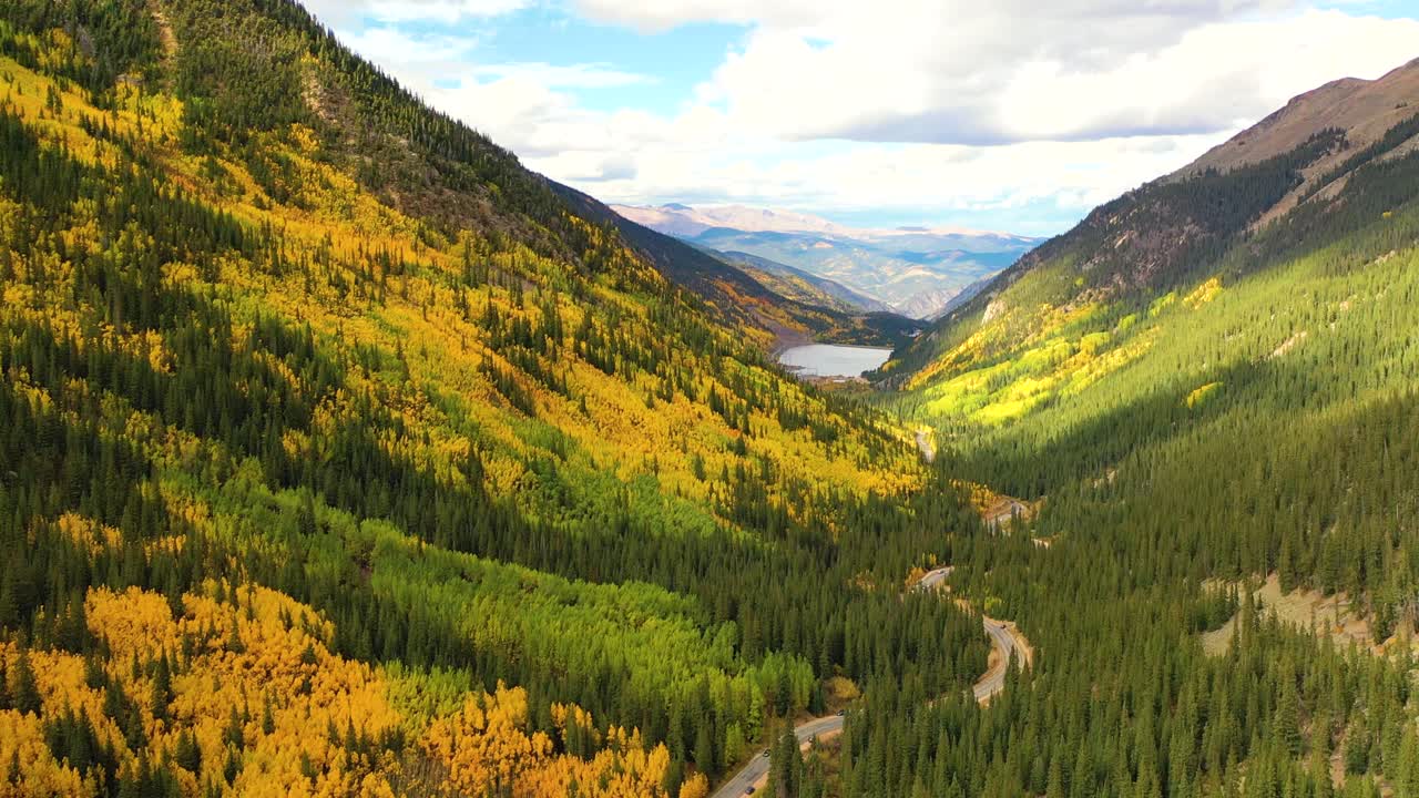Silverton, Colorado bursts with color as cars wind through bright aspen groves and narrow mountain switchbacks framed by rugged peaks and clear blue sky
