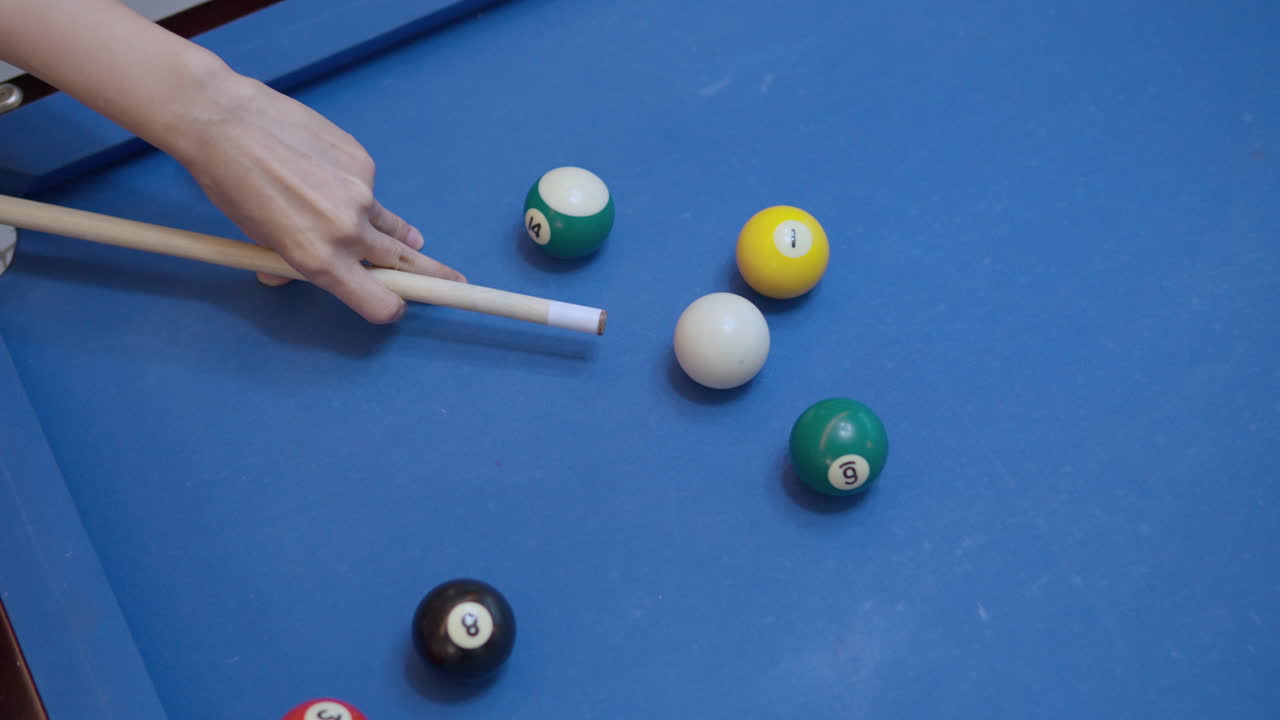 el jugador apunta de cerca y golpea la pelota blanca sobre la mesa de billar azul en cámara lenta vista superior