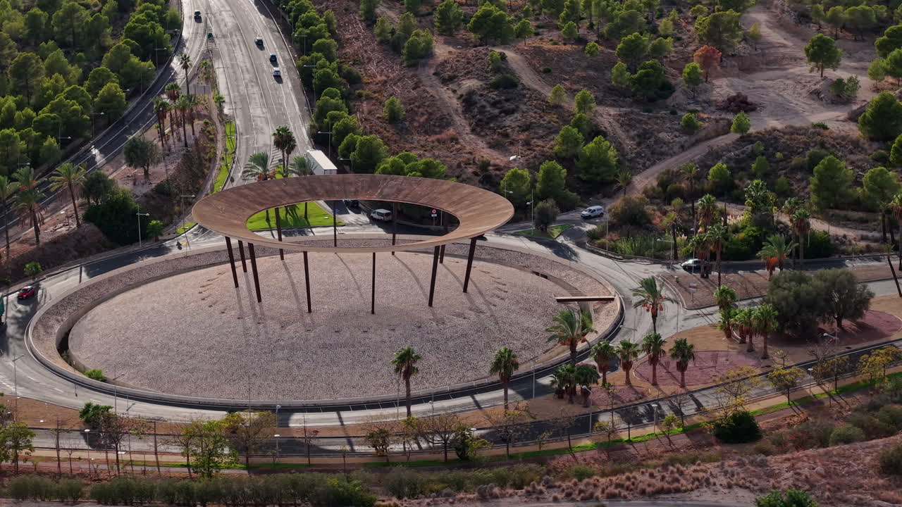 Vista aerea di una rotonda moderna con struttura architettonica circolare e strade trafficate vicino a Benidorm, circondata da paesaggio urbano