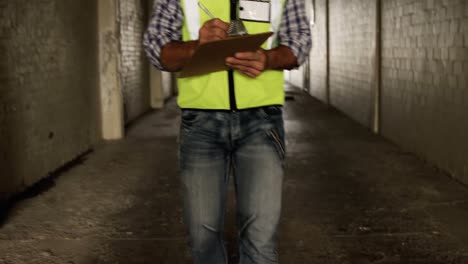 Welder-writing-on-clipboard-while-walking-in-corridor