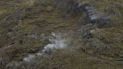 Steam-flows-from-cracks-in-volcanic-surface-of-Iceland,-aerial
