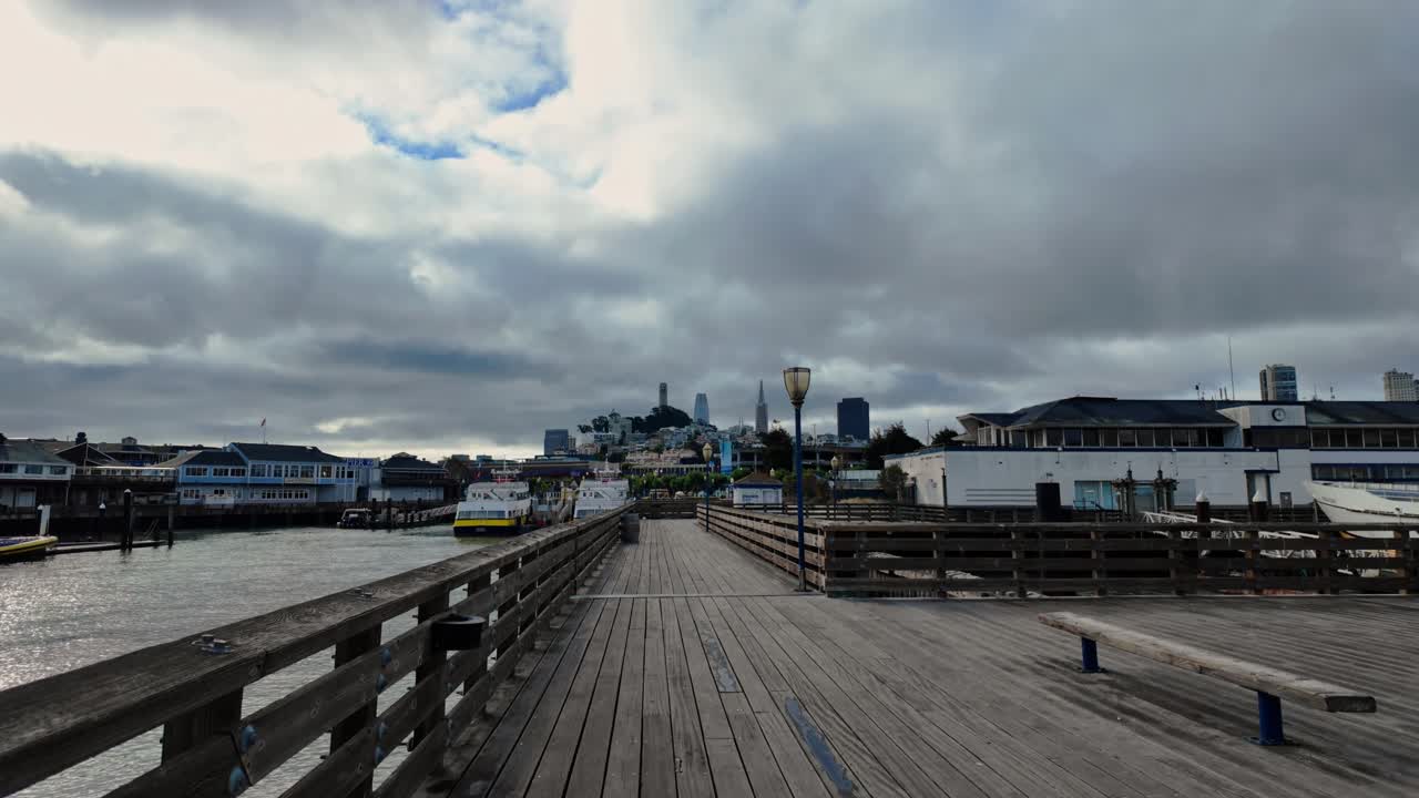 Walking on Pier 41 with San Francisco skyline and Coit Tower in the background on a cloudy day