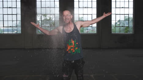 slow motion footage of a man with flour in his hands dancing and yelling in an industrial setting.