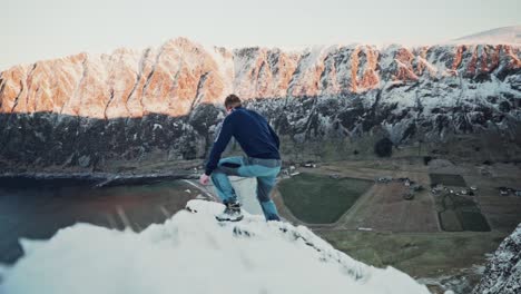 zeitlupenaufnahme eines jungen mannes, der auf einem sehr schmalen bergvorsprung läuft, während in der ferne die wunderschöne sonne auf die berggipfel scheint