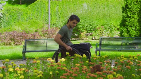 disabled young man driving his wheelchair touches flowers.