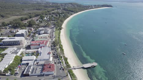 Vista-Aérea-De-Los-Edificios-Frente-Al-Mar-En-La-Playa-De-Shoal-Bay-Con-Embarcadero-Durante-El-Verano-En-Nsw,-Australia