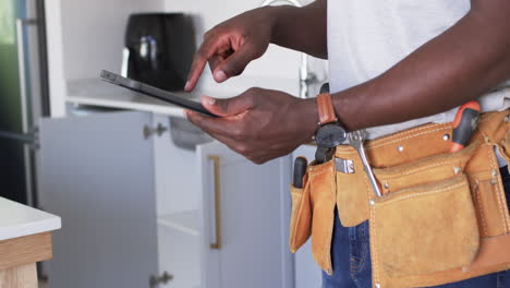 african american handyman is browsing a tablet in a kitchen