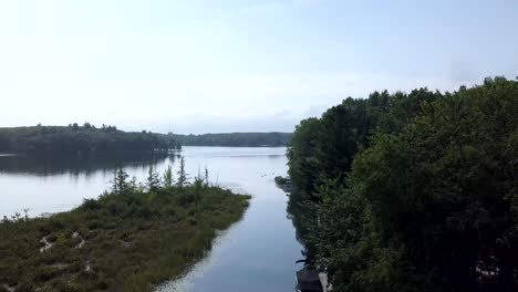 4k scenic clip rising up from a canal to show the lake and trees and nature on a sunny summer day outdoors with a light blue sky