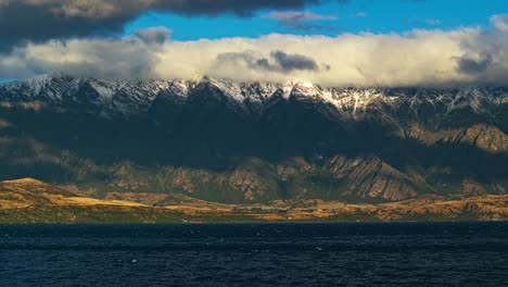 layered mountain landscape sloping from sky clouds to snow and forest above lake wakatipu