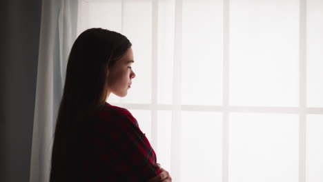 pretty teenage girl with long hair stands near french window