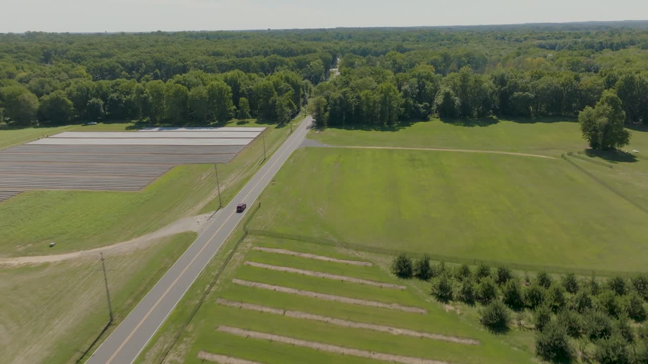 A car drives along a scenic country road, ideal for travel, automotive, countryside, and rural road visuals
