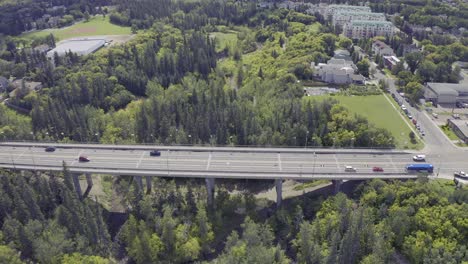 aerial-fly-over-international-concrete-flag-bridge-over-a-river-valley-park-for-cyclists-triathlon-fitness-training-people-next-to-low-rise-luxury-townhome-apartments-with-a-baseball-park-river-rapids