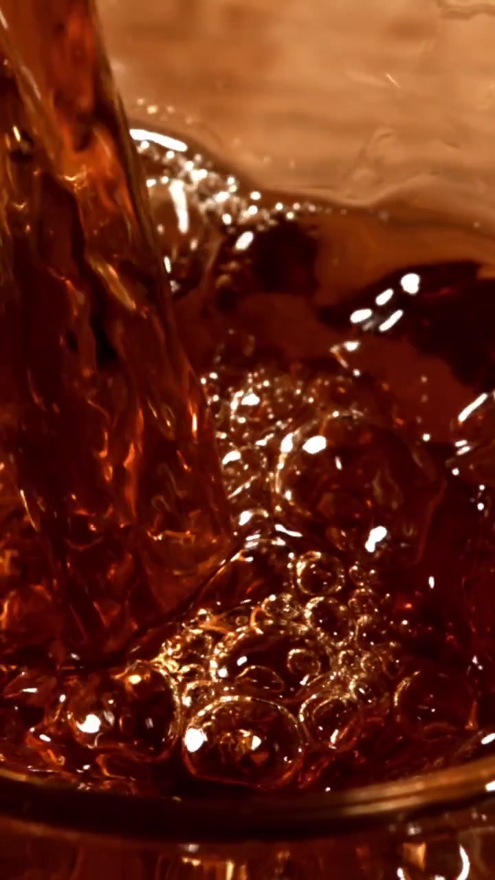 Primo piano di liquido ambrato che si versa e ribolle.