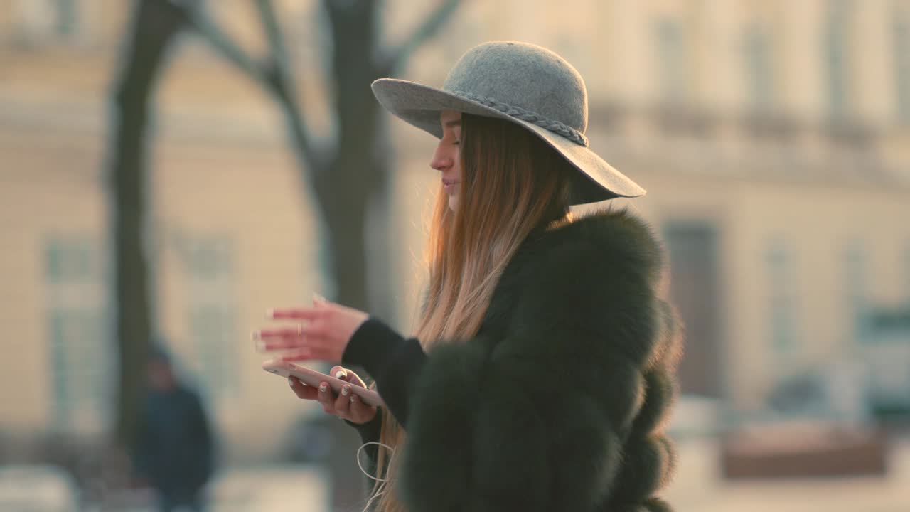 una joven hermosa a la luz del sol usa su teléfono.