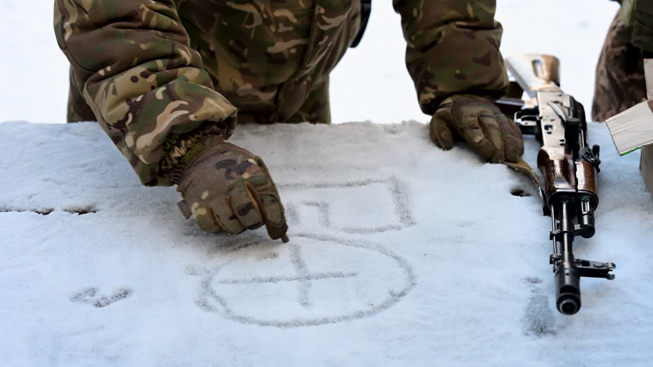 In Ukraine, a military instructor draws tactics in the snow during training. This close-up highlights crucial strategic planning and combat readiness amidst challenging winter and war's impact.