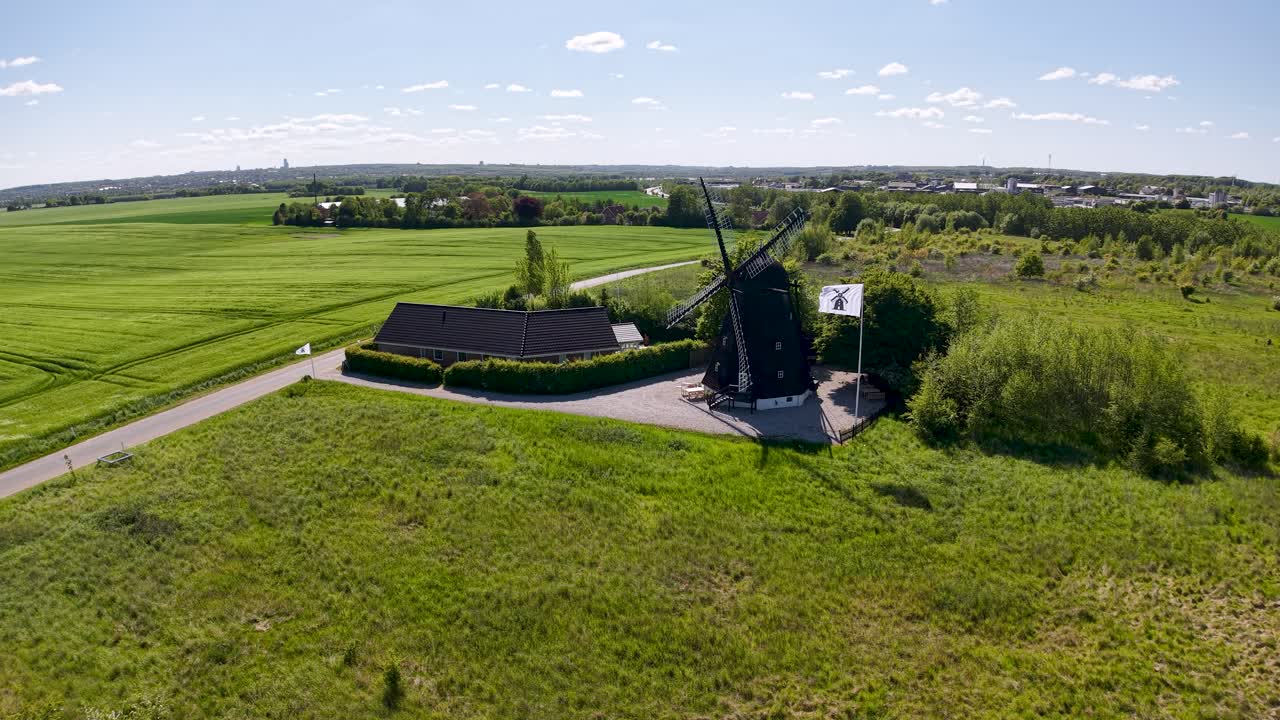 Aerial drone footage of Ega Mill in Denmark surrounded by green farmland and open countryside under a bright summer sky