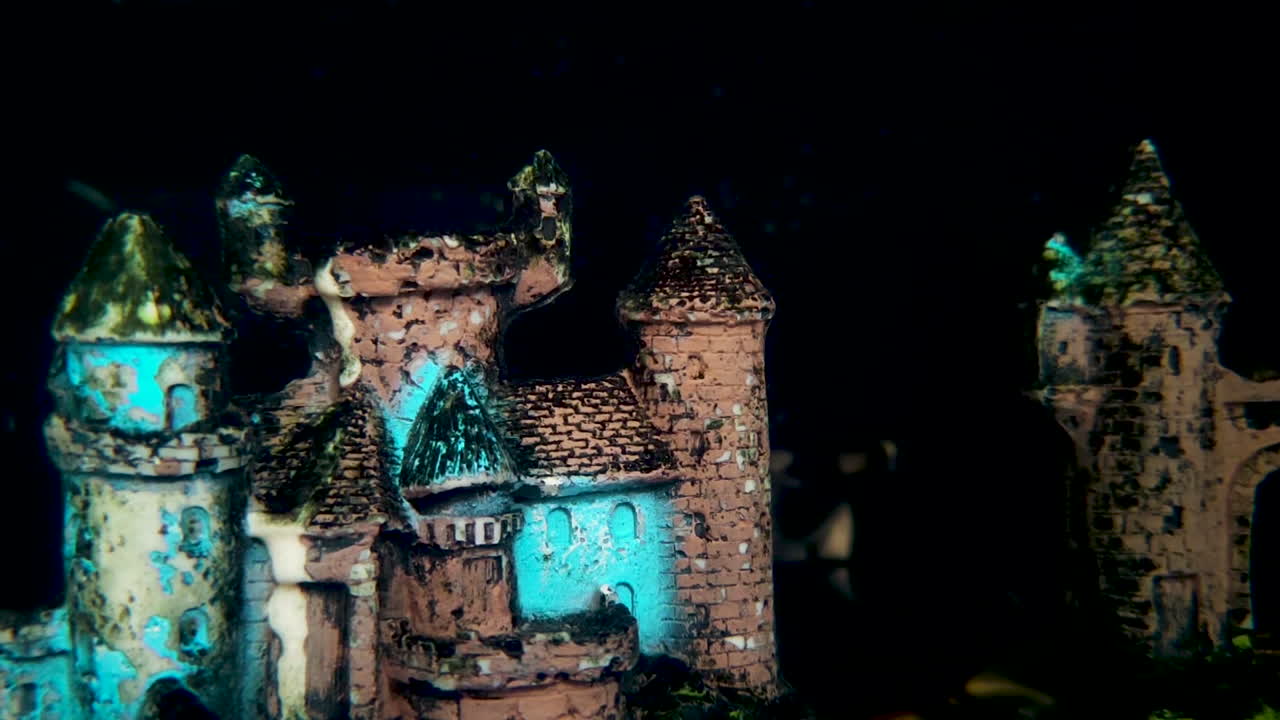 aquarium castle decoration with glowing lights in dark water close-up footage. Great for aquarium themes, underwater visuals, relaxation and creative video projects