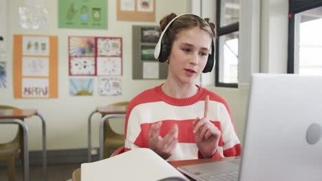 On video call, In school, girl wearing headphones engaging in online class discussion