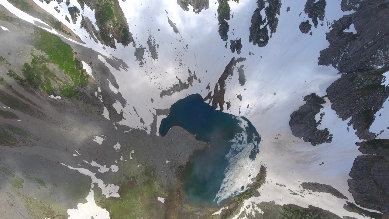 Vista aerea di un lago alpino circondato da montagne innevate